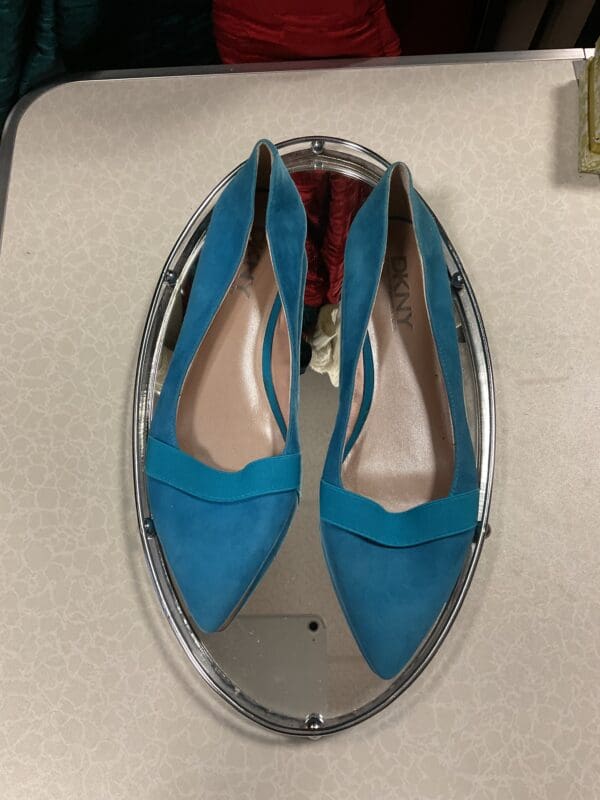 A pair of blue shoes sitting on top of a mirror.