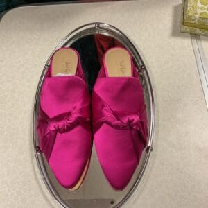 A pair of pink shoes sitting on top of a mirror.