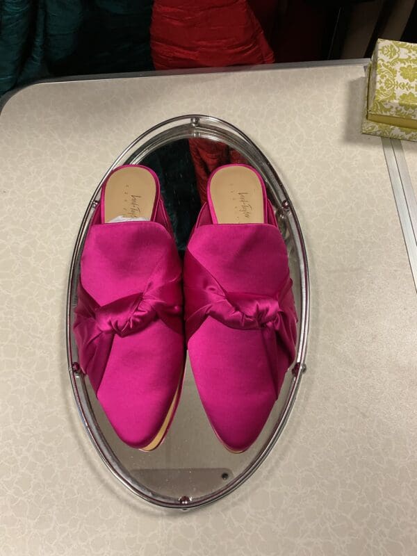 A pair of pink shoes sitting on top of a mirror.