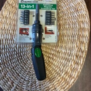 A green screwdriver sitting on top of a woven basket.