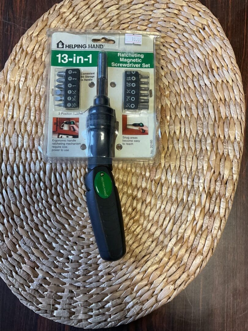 A green screwdriver sitting on top of a woven basket.